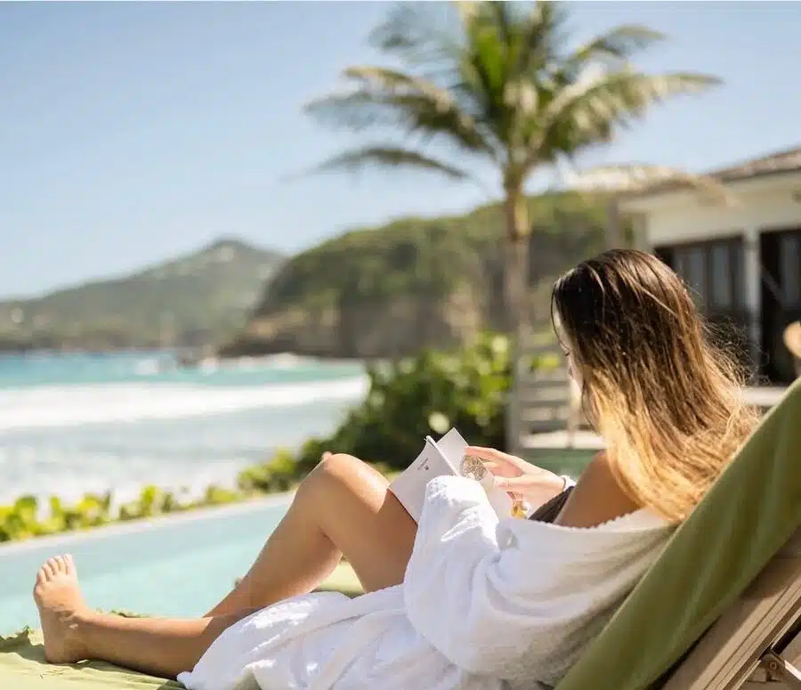 Femme élégante en peignoir ultra luxueux en fibre de bambou, profitant d'un moment de détente sur la terrasse d'une piscine, entourée d'un cadre raffiné et apaisant.